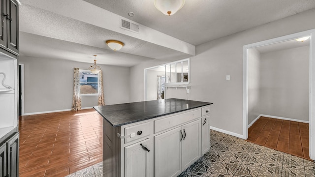 kitchen featuring dark wood-type flooring, white cabinets, and a textured ceiling