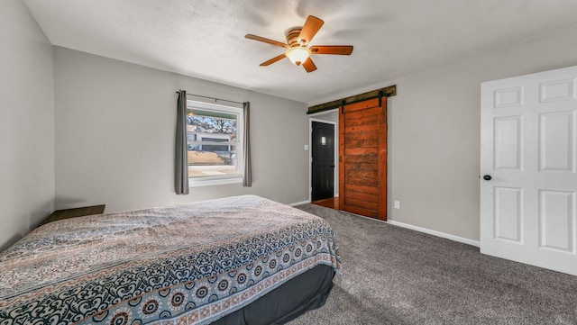 bedroom featuring ceiling fan, a barn door, and carpet floors