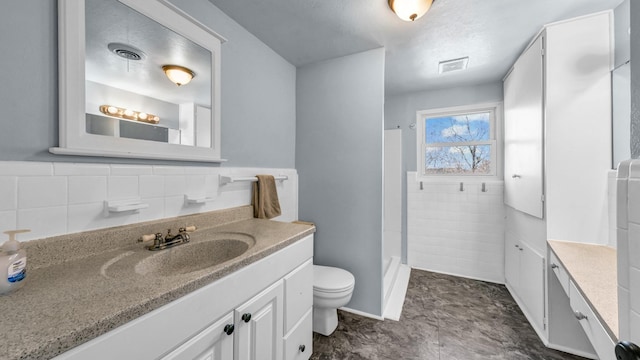 bathroom with walk in shower, vanity, toilet, and tile walls