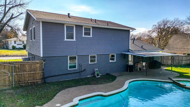 back of house featuring a swimming pool with hot tub and a patio area