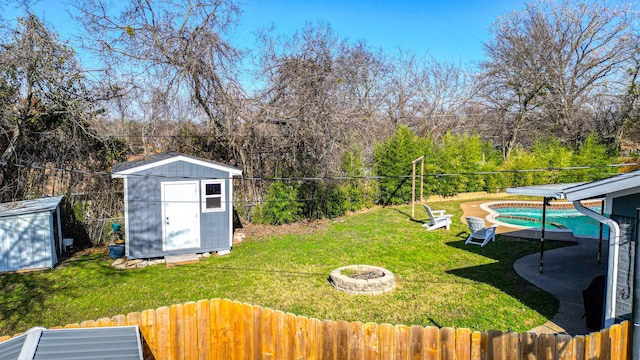 view of yard featuring an outdoor fire pit, a fenced in pool, and a shed