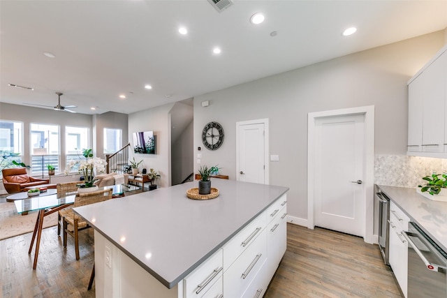 kitchen featuring dishwasher, white cabinets, decorative backsplash, ceiling fan, and a kitchen island