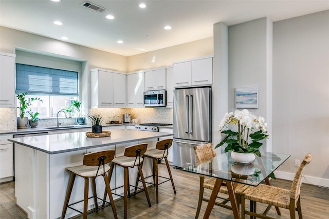 kitchen with white cabinetry, a center island, stainless steel appliances, and sink