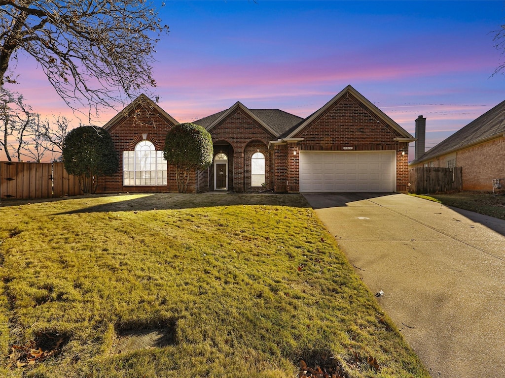 single story home featuring a garage and a lawn