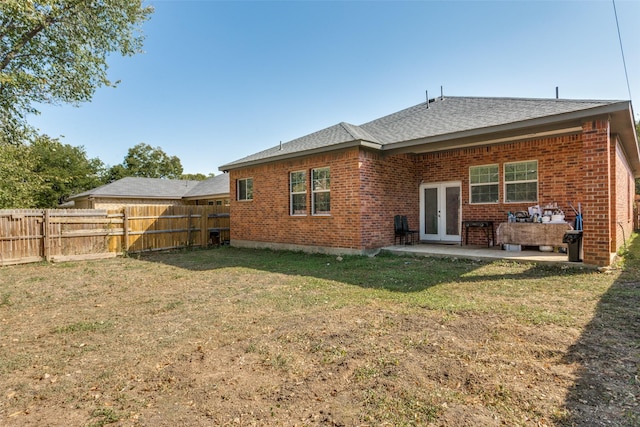 back of property with a yard, a patio, and french doors