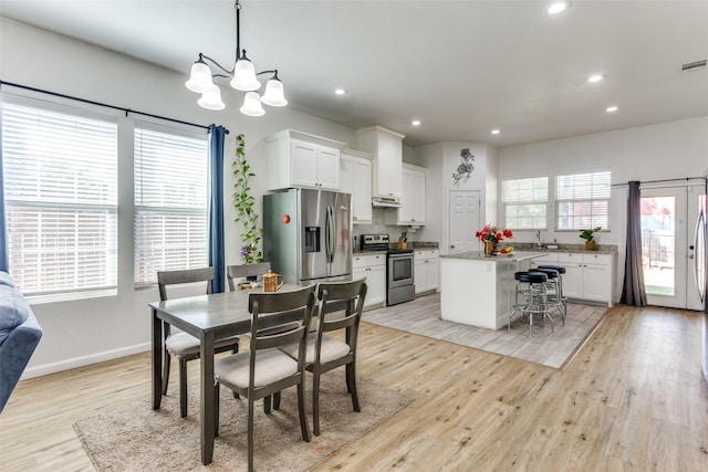 dining area with light wood-type flooring and a chandelier