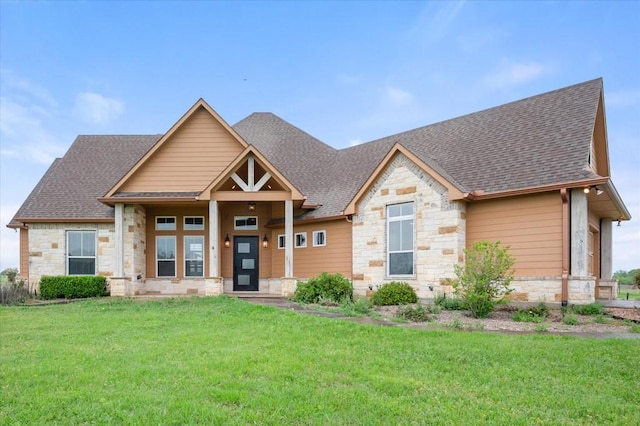 craftsman-style house featuring stone siding, a front lawn, and roof with shingles