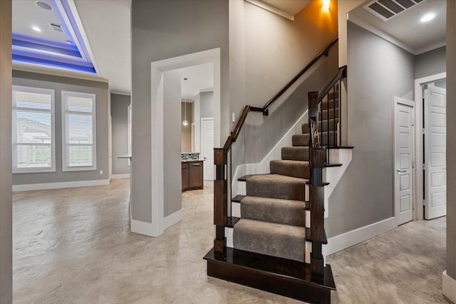 staircase featuring visible vents, crown molding, baseboards, and finished concrete floors