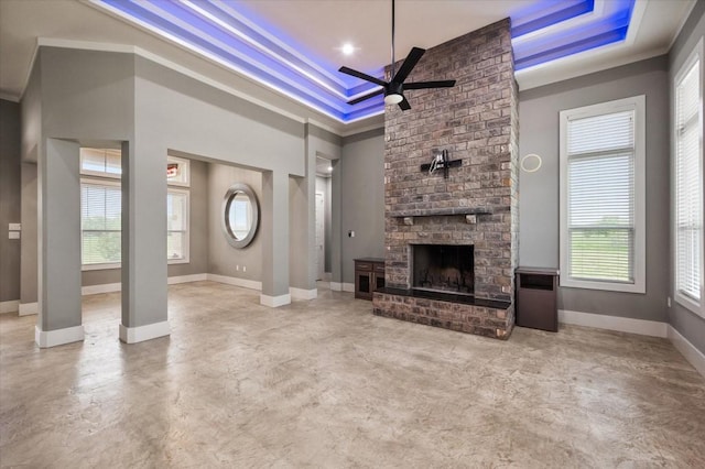 unfurnished living room with plenty of natural light, a tray ceiling, and ceiling fan