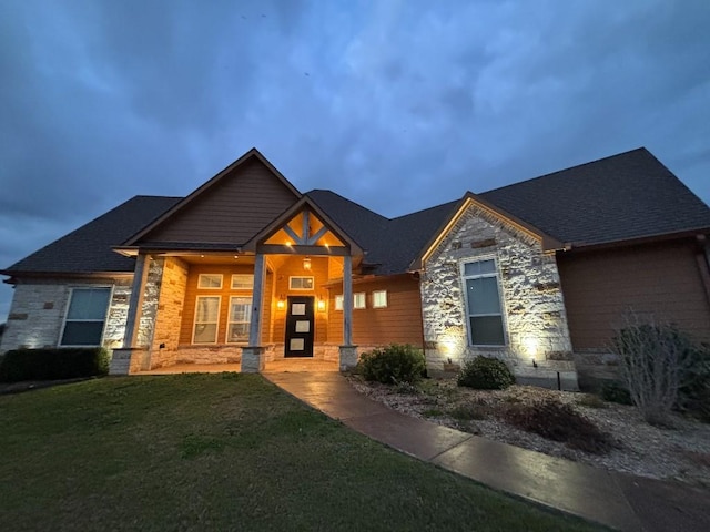 craftsman-style house with stone siding and a front lawn