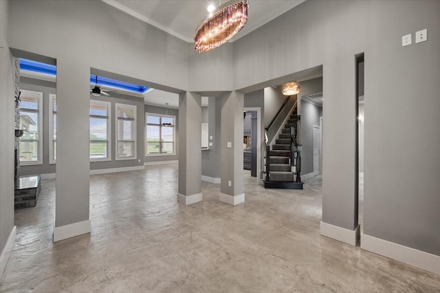 entryway featuring stairs, finished concrete flooring, baseboards, and a towering ceiling