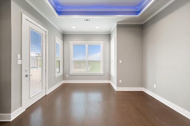 interior space featuring a raised ceiling, visible vents, dark wood-style floors, and ornamental molding