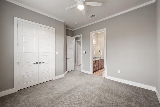 unfurnished bedroom featuring baseboards, visible vents, light colored carpet, a closet, and crown molding