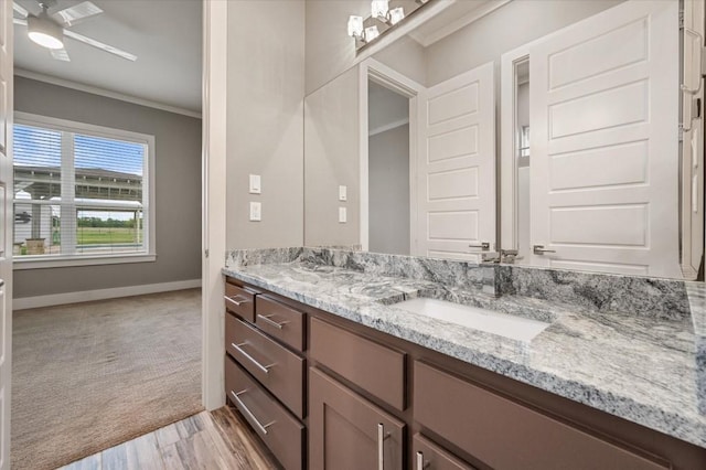 bathroom with a ceiling fan, crown molding, wood finished floors, vanity, and baseboards