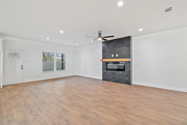 unfurnished living room featuring a fireplace, light wood-type flooring, and ceiling fan