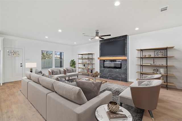 living room featuring a fireplace, light hardwood / wood-style floors, and ceiling fan