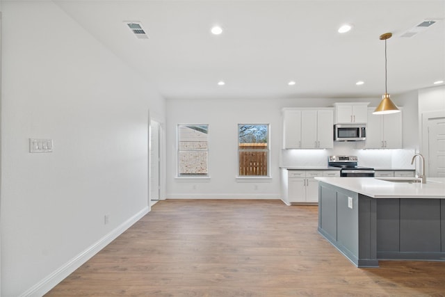 kitchen with backsplash, white cabinets, sink, hanging light fixtures, and stainless steel appliances