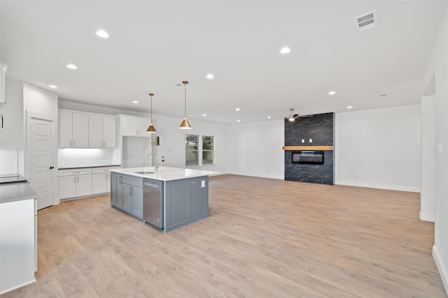 kitchen with white cabinetry, ceiling fan, sink, decorative light fixtures, and a center island with sink