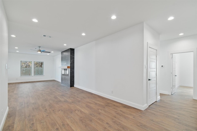 unfurnished living room featuring light wood-type flooring, ceiling fan, and a premium fireplace