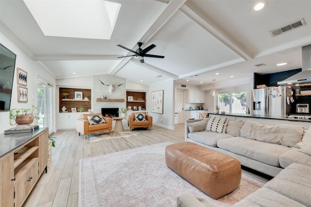 living room with a fireplace, lofted ceiling with skylight, and ceiling fan