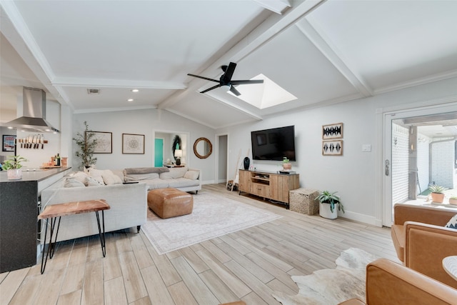 living room featuring crown molding, vaulted ceiling with skylight, and ceiling fan