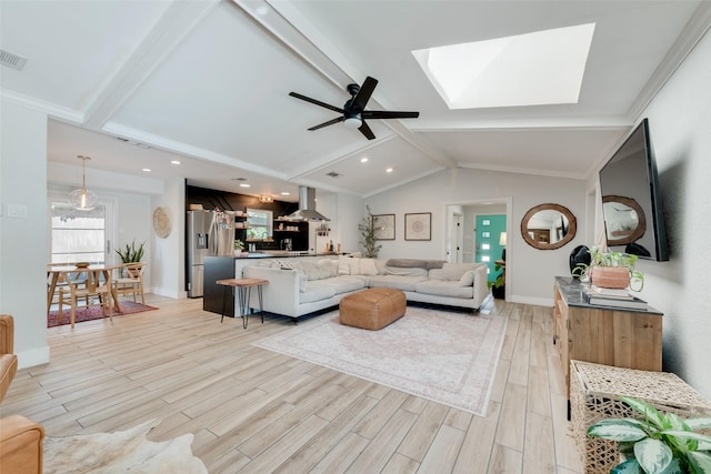 living room with ornamental molding, vaulted ceiling with skylight, ceiling fan, and light hardwood / wood-style floors