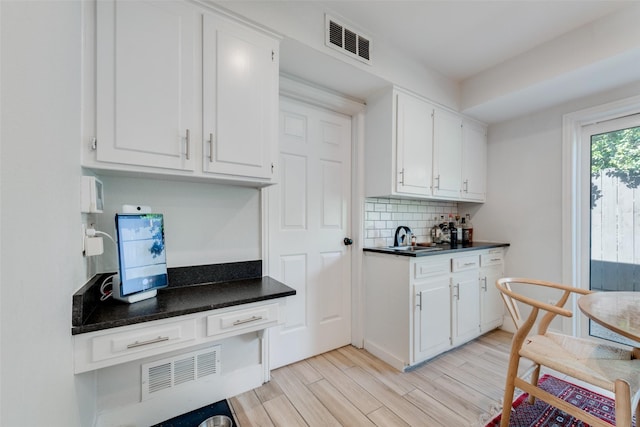 kitchen featuring white cabinetry, sink, decorative backsplash, and light wood-type flooring