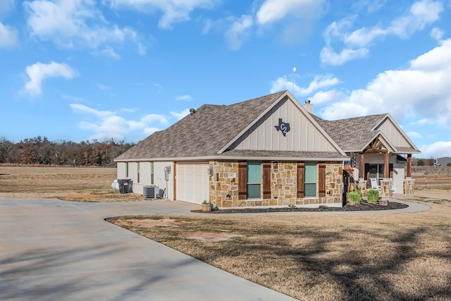 view of front of home with central AC unit, a garage, covered porch, and a front lawn