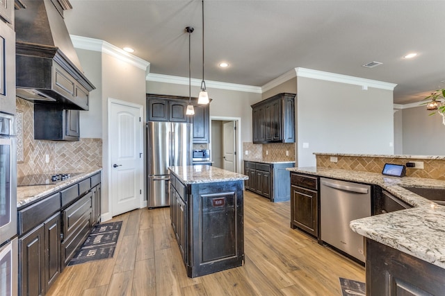 kitchen featuring backsplash, dark brown cabinetry, stainless steel appliances, decorative light fixtures, and a kitchen island