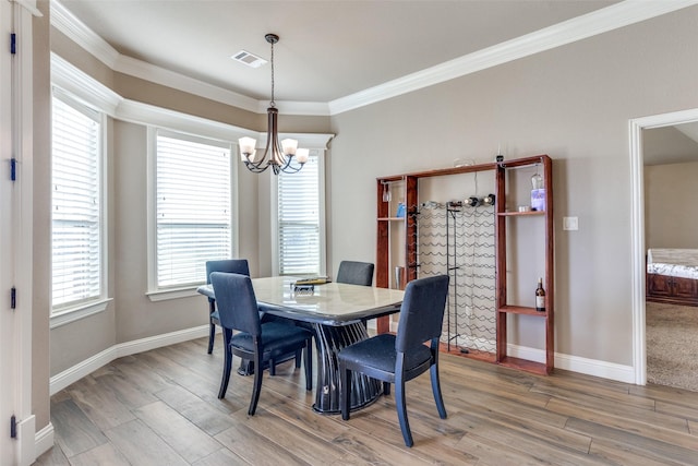 dining area featuring hardwood / wood-style floors, plenty of natural light, ornamental molding, and a chandelier