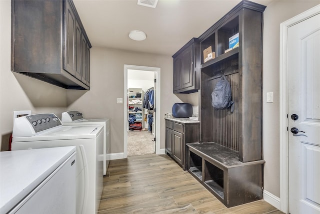 laundry area featuring washer and dryer, light hardwood / wood-style floors, and cabinets