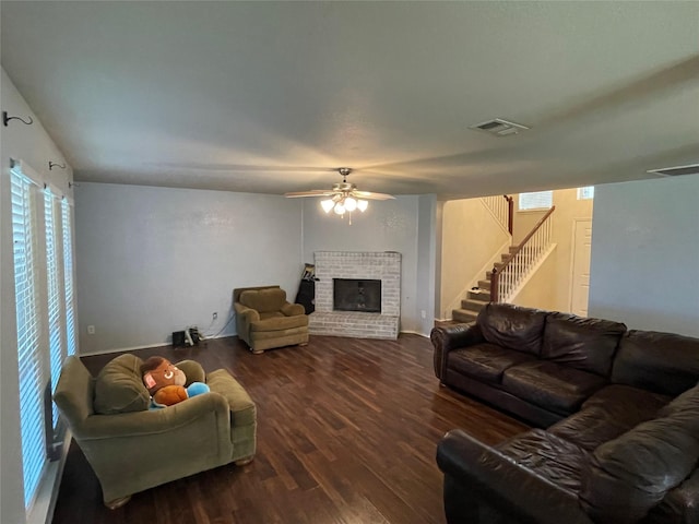 living room with dark hardwood / wood-style flooring, a brick fireplace, and ceiling fan