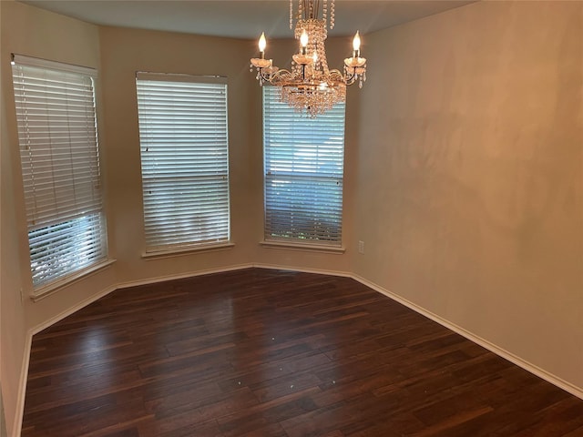 spare room with dark hardwood / wood-style flooring and a chandelier