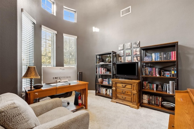 office featuring carpet and a towering ceiling