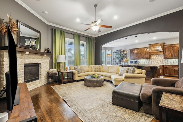 living room featuring ceiling fan, crown molding, and a fireplace