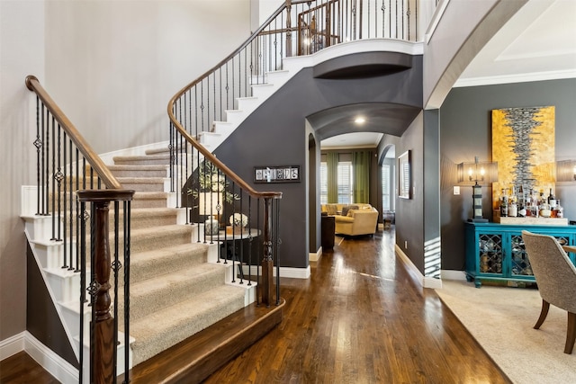 foyer entrance featuring bar area, a high ceiling, ornamental molding, and dark hardwood / wood-style floors