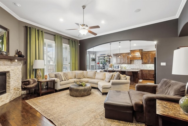 living room featuring ceiling fan, a fireplace, ornamental molding, and hardwood / wood-style flooring