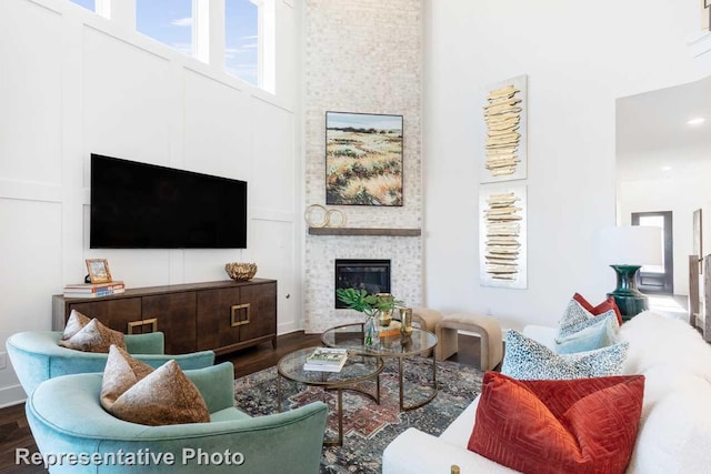 living room with a large fireplace, a towering ceiling, and hardwood / wood-style flooring