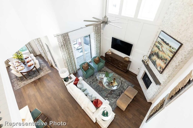 living room with a wealth of natural light, a towering ceiling, ceiling fan, and dark hardwood / wood-style floors