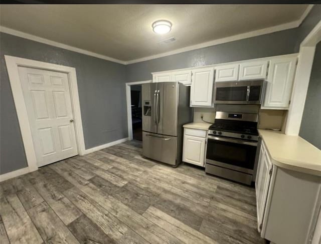 kitchen featuring appliances with stainless steel finishes, light hardwood / wood-style flooring, white cabinetry, and crown molding