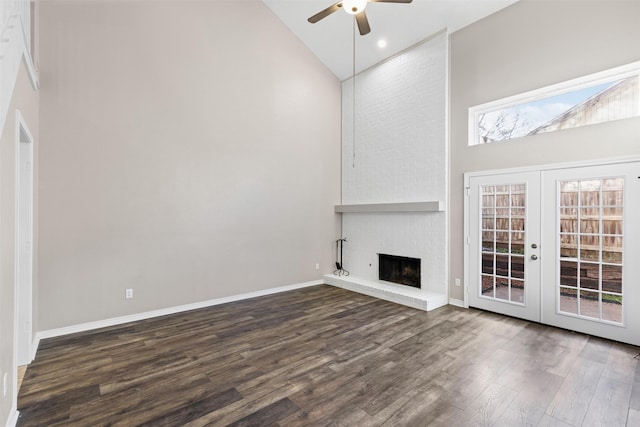 unfurnished living room with a fireplace, high vaulted ceiling, dark wood-type flooring, and french doors