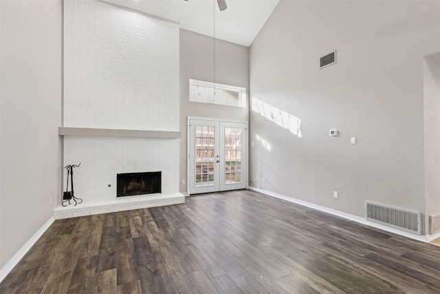 unfurnished living room with ceiling fan, a towering ceiling, dark wood-type flooring, and french doors