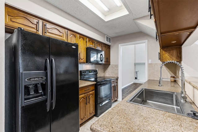 kitchen featuring backsplash, a textured ceiling, sink, black appliances, and light tile patterned floors