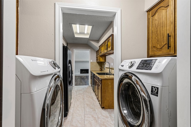 laundry area with a textured ceiling, sink, and washing machine and clothes dryer