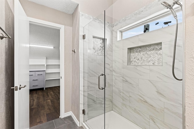 bathroom featuring tile patterned floors, a shower with door, and a textured ceiling