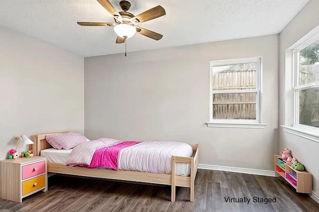 bedroom with ceiling fan, dark wood-type flooring, and a textured ceiling