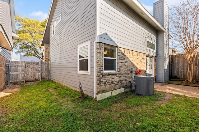 view of side of property featuring central AC unit and a yard