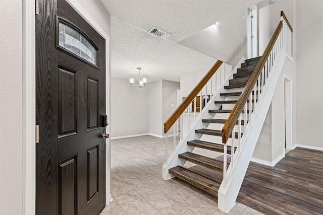 tiled foyer featuring a chandelier and a textured ceiling