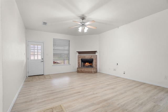 unfurnished living room with ceiling fan, a fireplace, and light hardwood / wood-style flooring