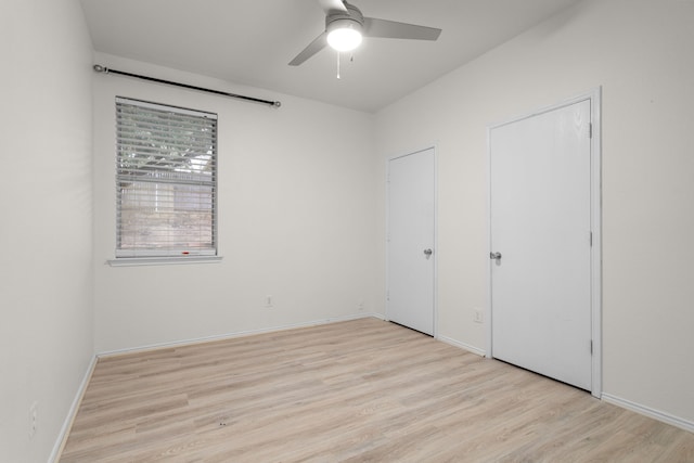 unfurnished bedroom featuring multiple closets, ceiling fan, and light wood-type flooring